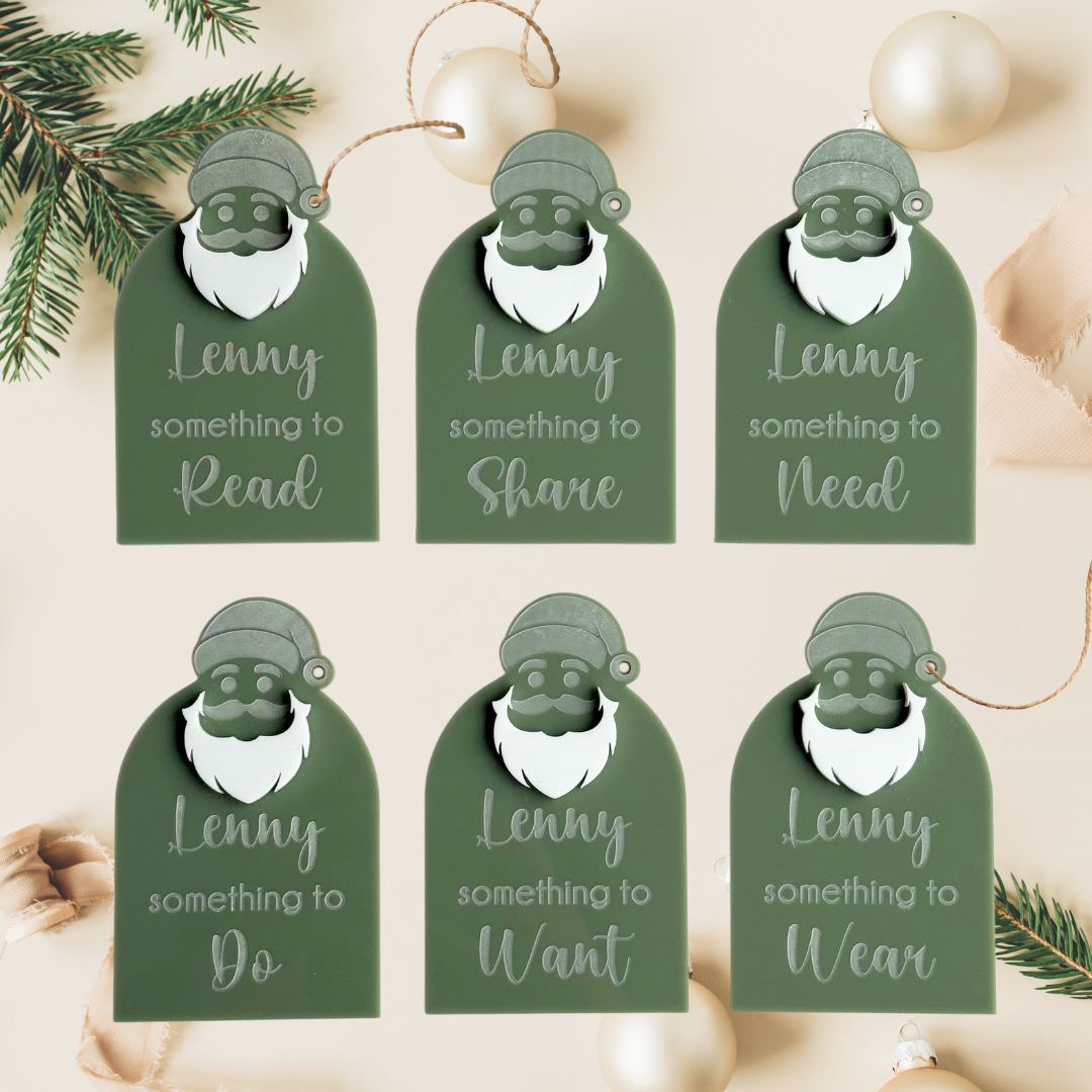 green acrylic personalised santa present tags with name and categories like something to read, want, wear, need displayed with christmas decorations