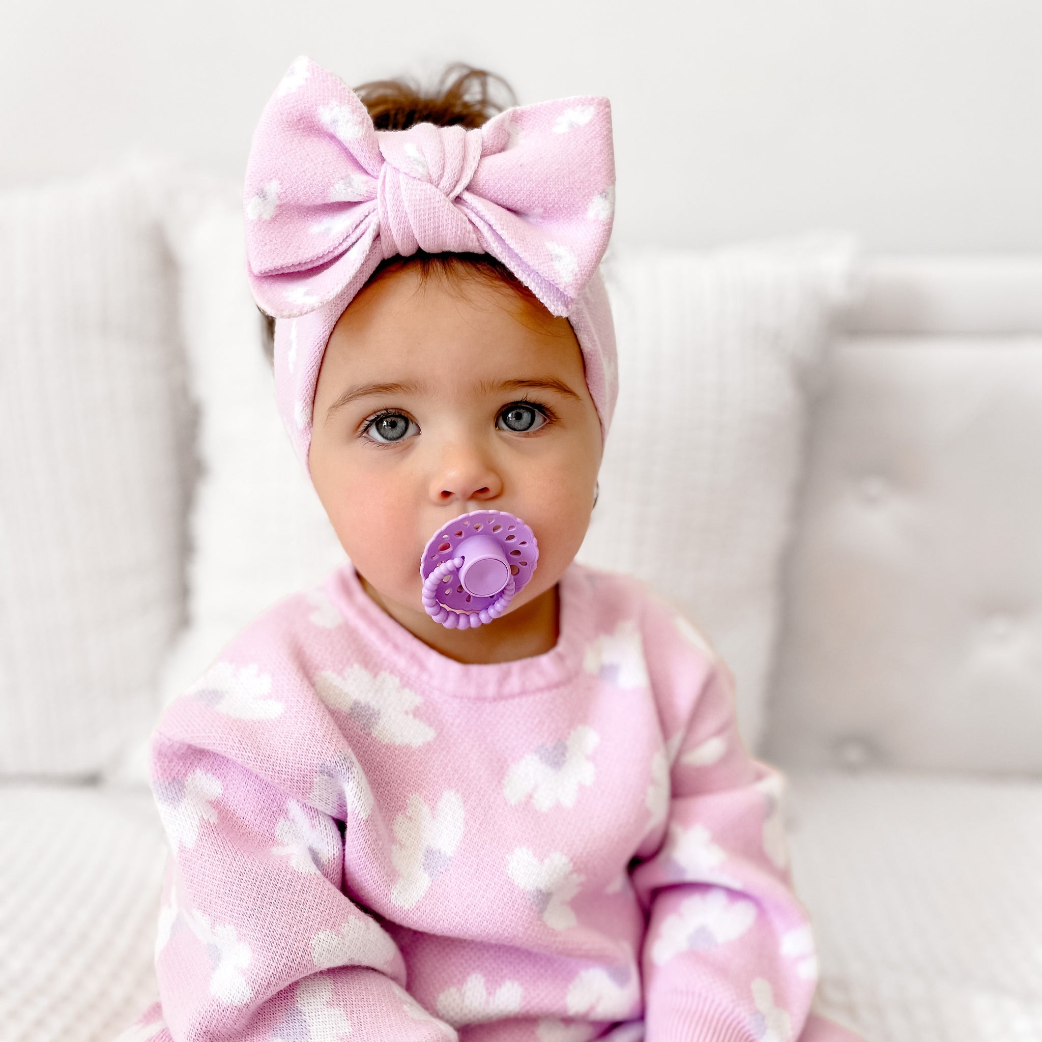 Baby girl wearing a pink outfit and headband using a lavender scalloped edge bloom cmc dummy with bubble handle