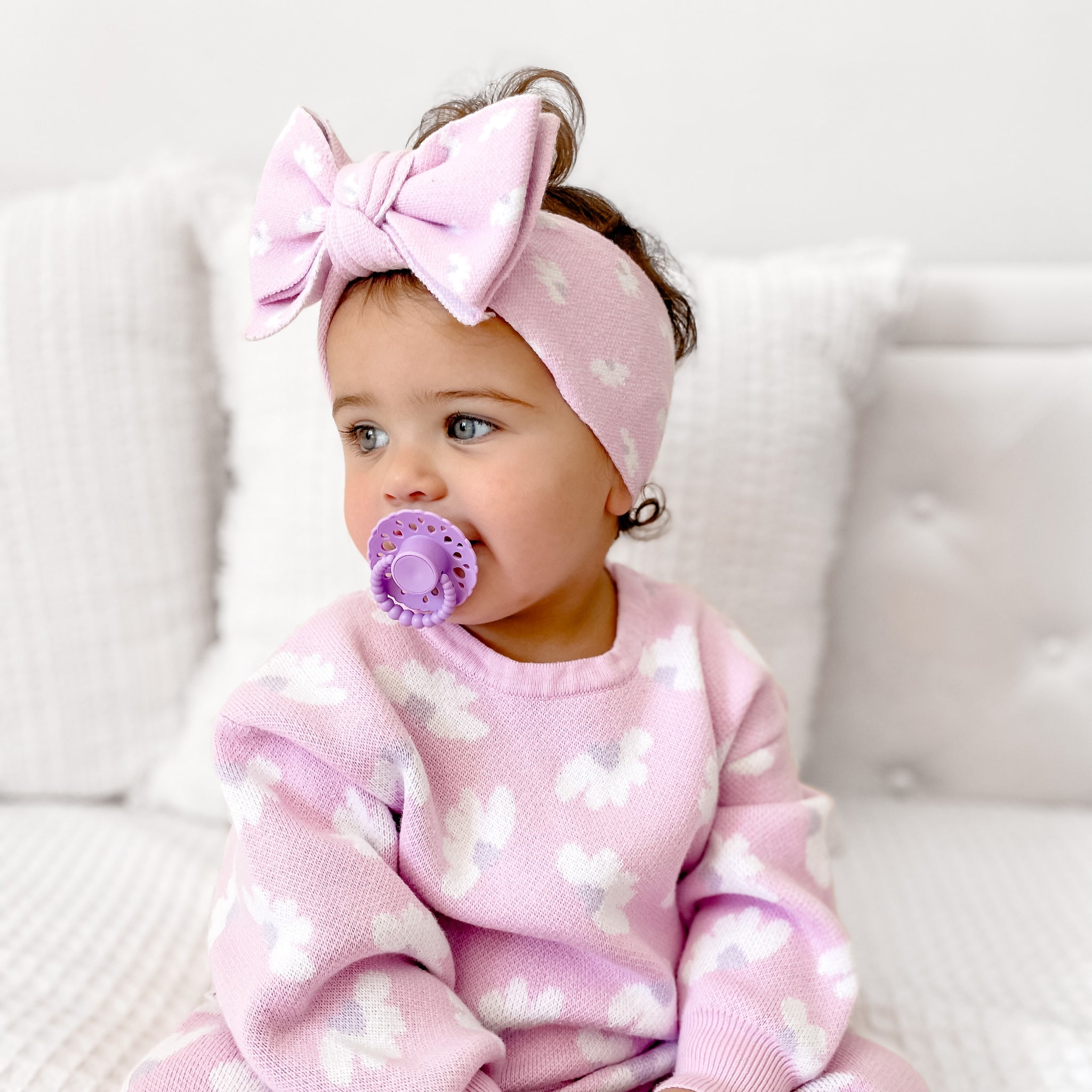 Baby girl wearing a pink outfit and headband using a lavender scalloped edge bloom cmc dummy with bubble handle