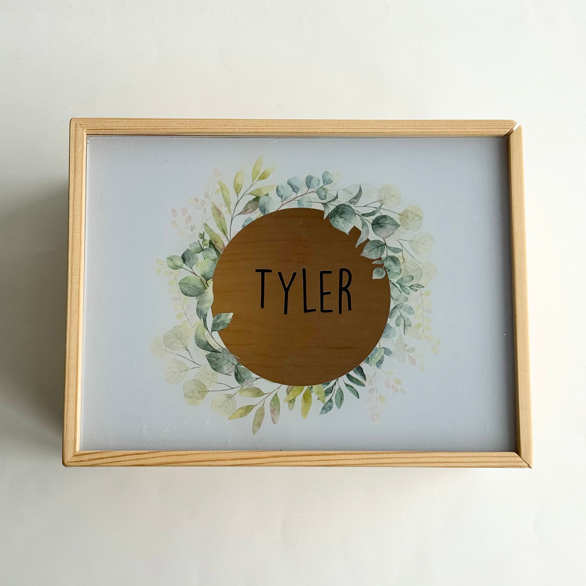 Personalised baby name frame with the name Tyler, featuring a wooden circular design and soft floral wreath in a natural timber frame