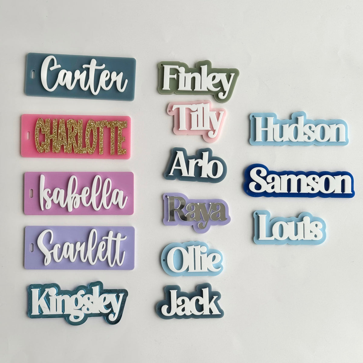 Assorted personalised acrylic name tags in various colours and fonts including Carter, Finley, Tilly and Hudson, custom kids labels on white background