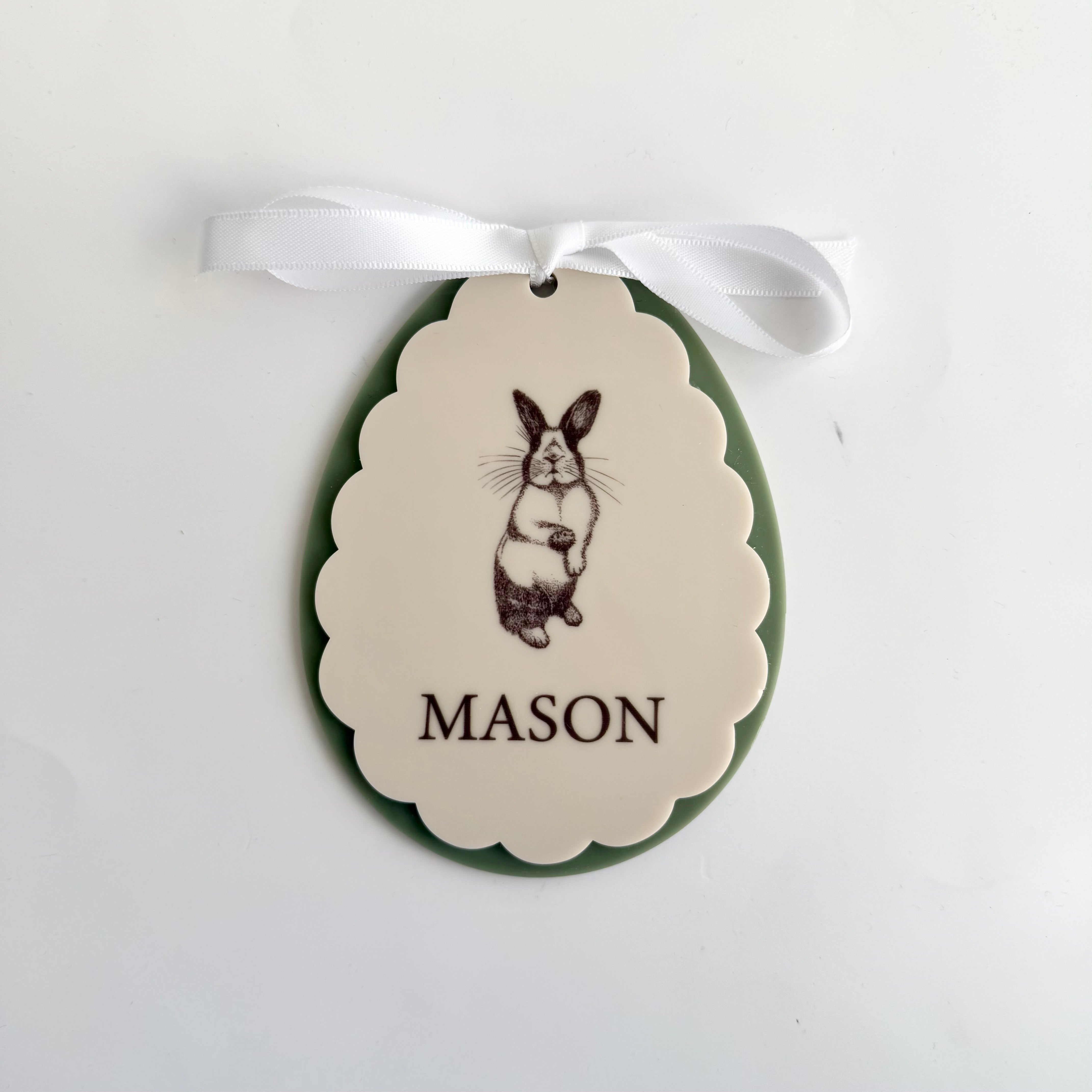 Personalised bunny keepsake ornament with name Mason, scalloped oval design with engraved rabbit illustration, white ribbon hanger and olive backing
