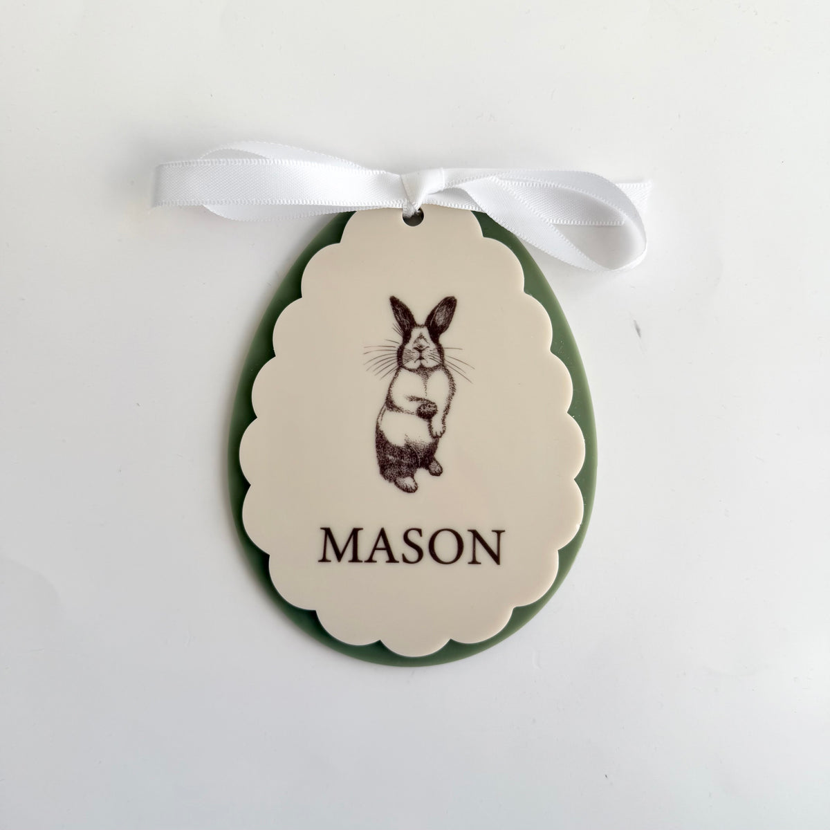 Personalised bunny keepsake ornament with name Mason, scalloped oval design with engraved rabbit illustration, white ribbon hanger and olive backing