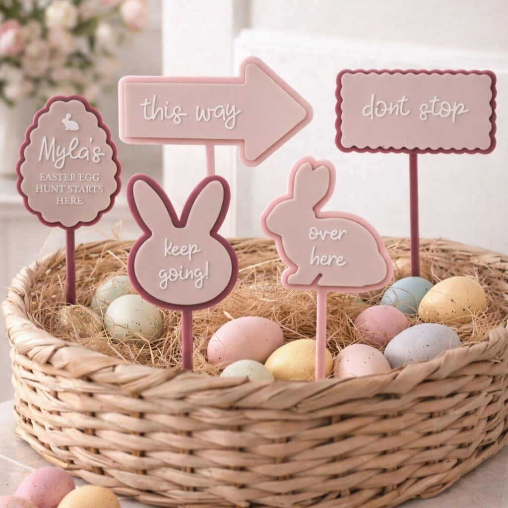 Personalised Easter egg hunt signs with arrows, bunny shapes and directions in a basket with pastel eggs