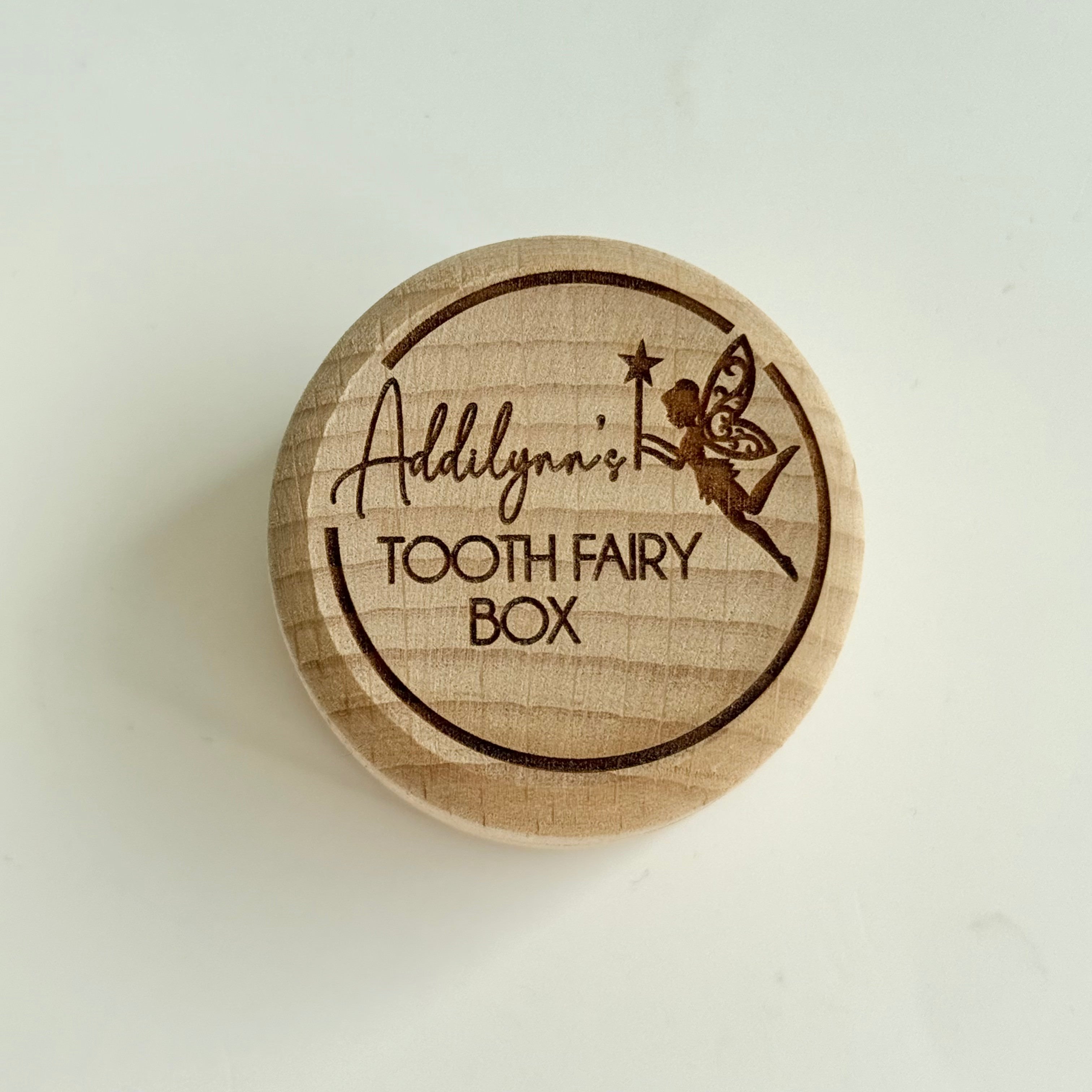 Personalised round wooden tooth fairy box engraved with fairy illustration and child’s name on lid