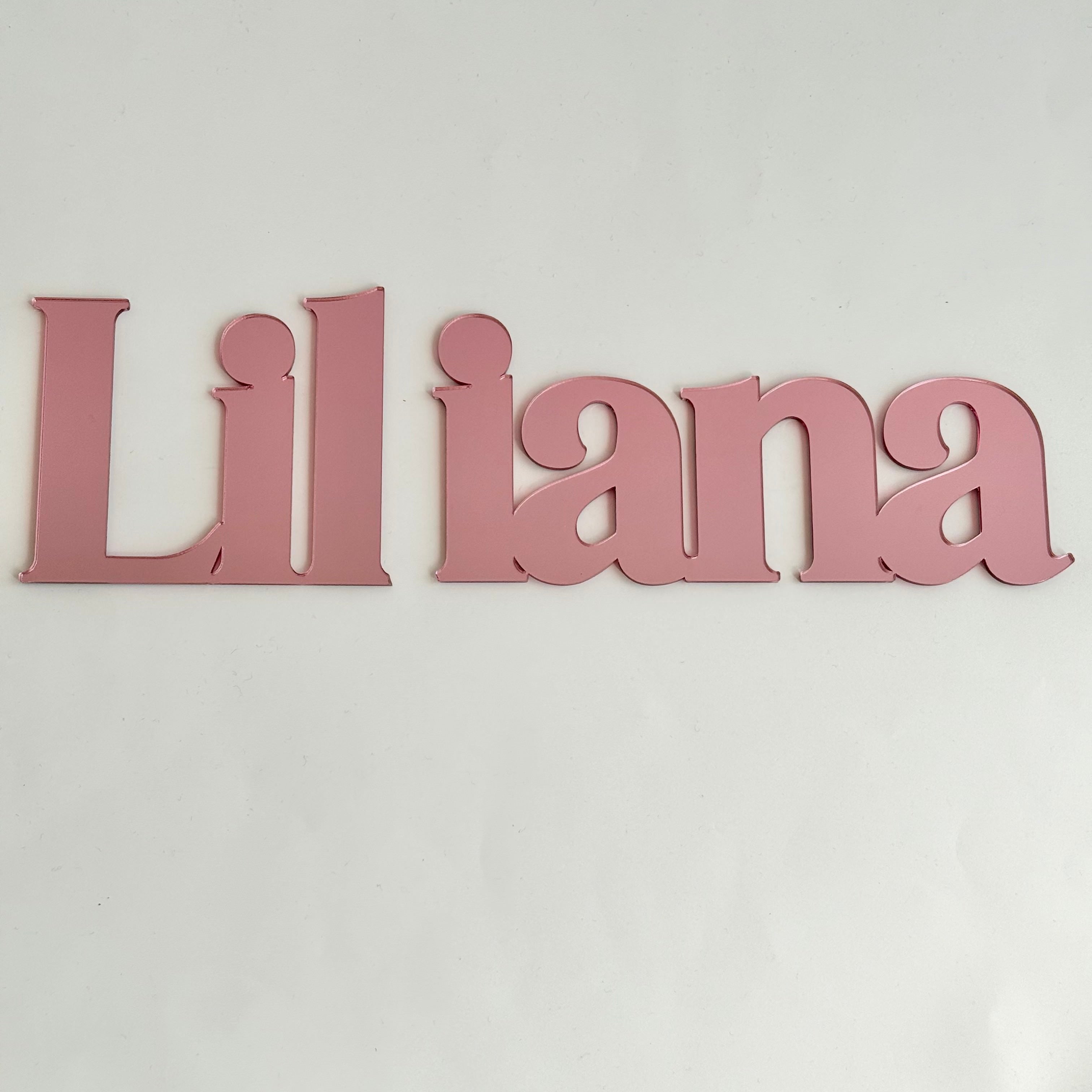 Personalised acrylic name sign reading Liliana in pink, designed as wall decor for a nursery or kids bedroom