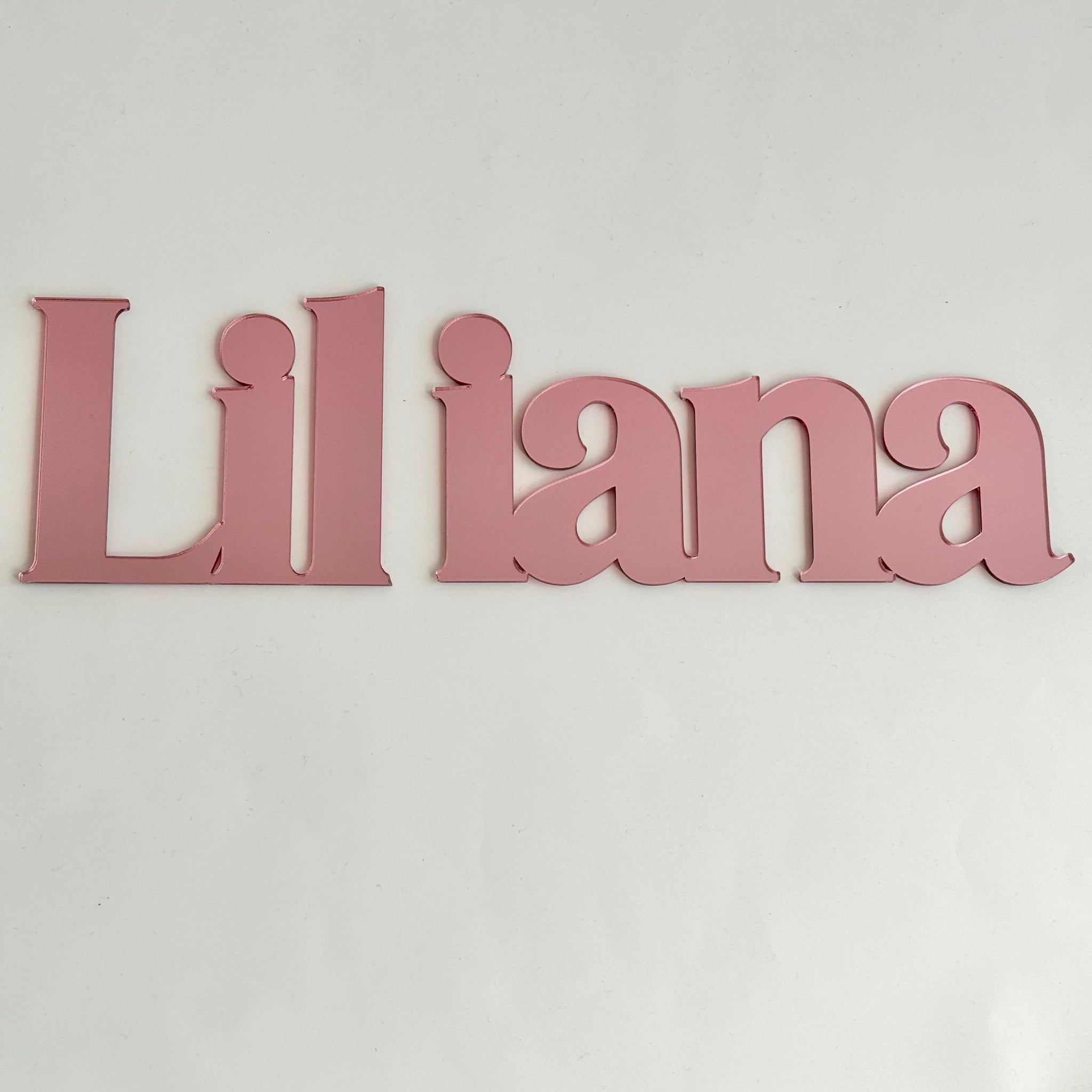Personalised acrylic name sign reading Liliana in pink, designed as wall decor for a nursery or kids bedroom