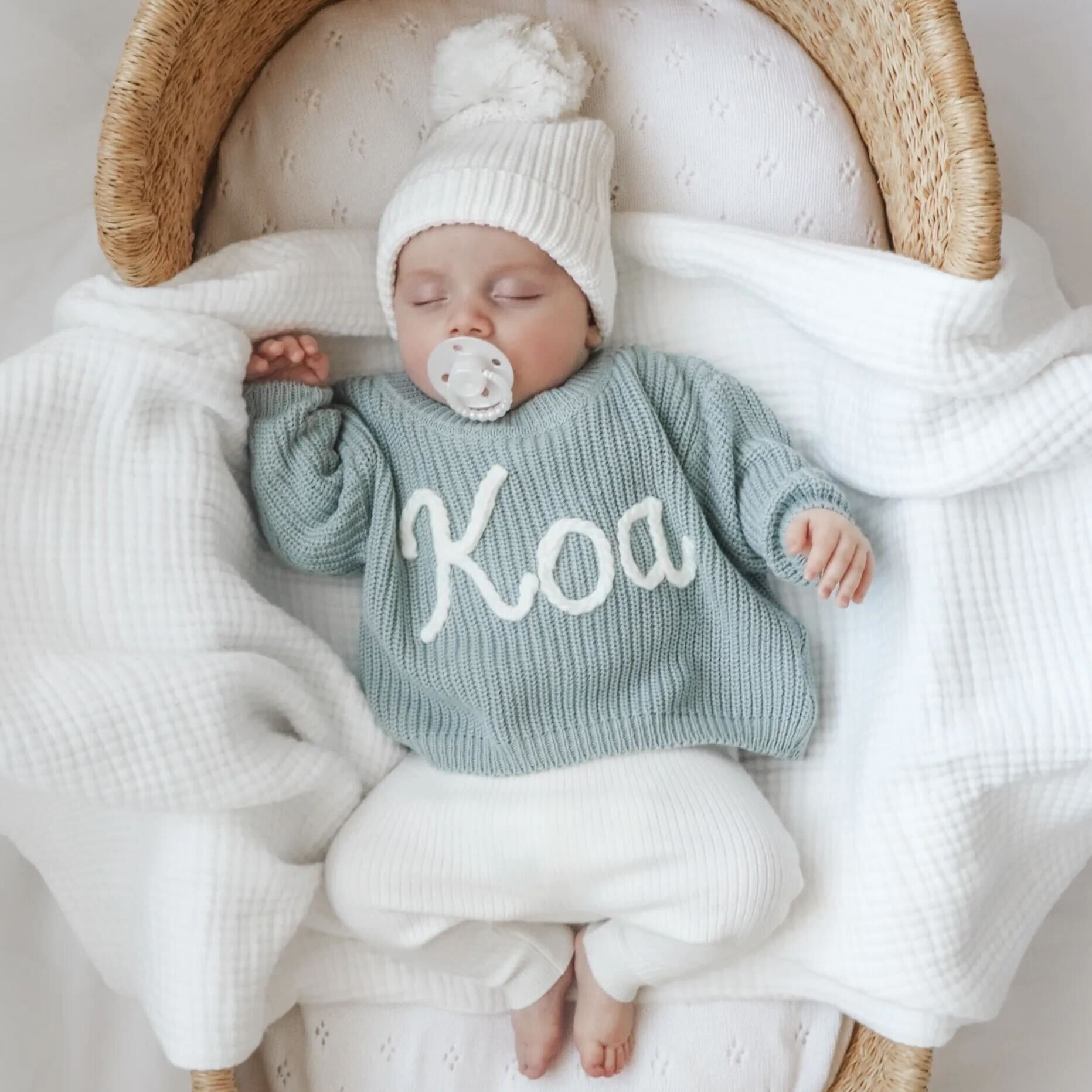 Sleeping newborn baby boy wearing personalised jumper with beanie and  a pearl white cmc bubble dummy.