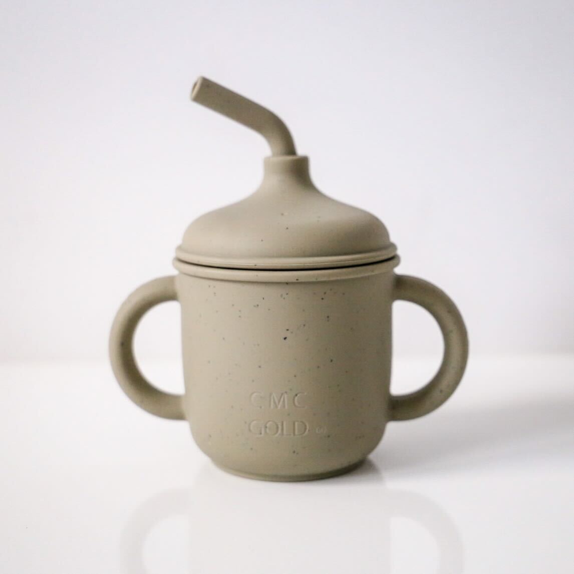 Sage green silicone sippy cup with handles and straw lid for babies and toddlers on a neutral background