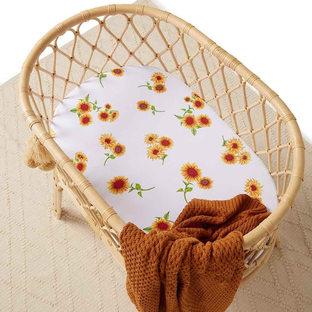 Baby bassinet with sunflower floral fitted sheet styled with rust knitted blanket