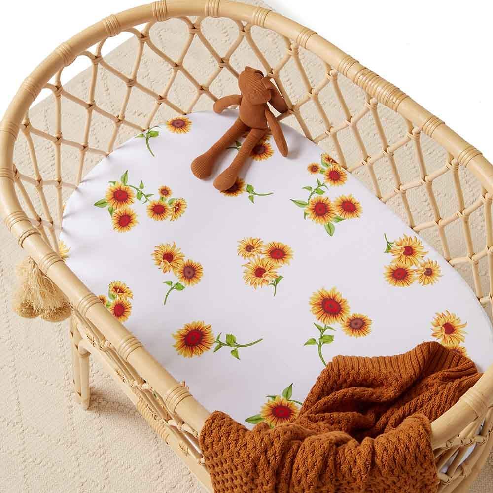 Baby bassinet with sunflower floral fitted sheet  styled with rust knitted blanket and teddy toy