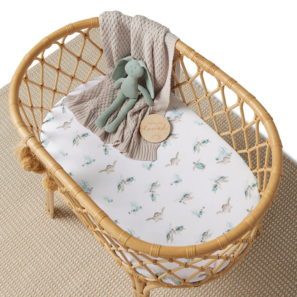 Baby bassinet sheet/change pad cover with sea turtle print styled with knitted blanket and soft toy in neutral nursery