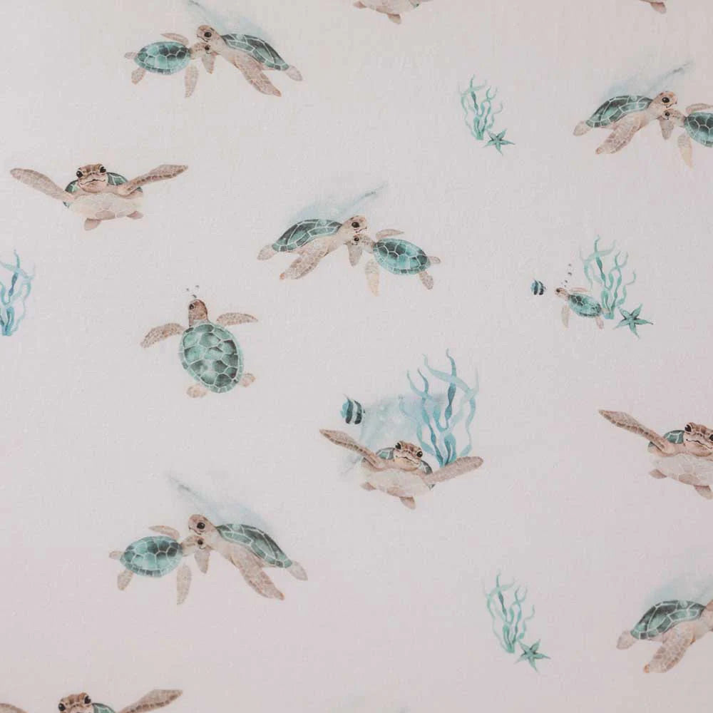 Close up of sea turtle pattern on baby cot sheet with soft ocean themed nursery print